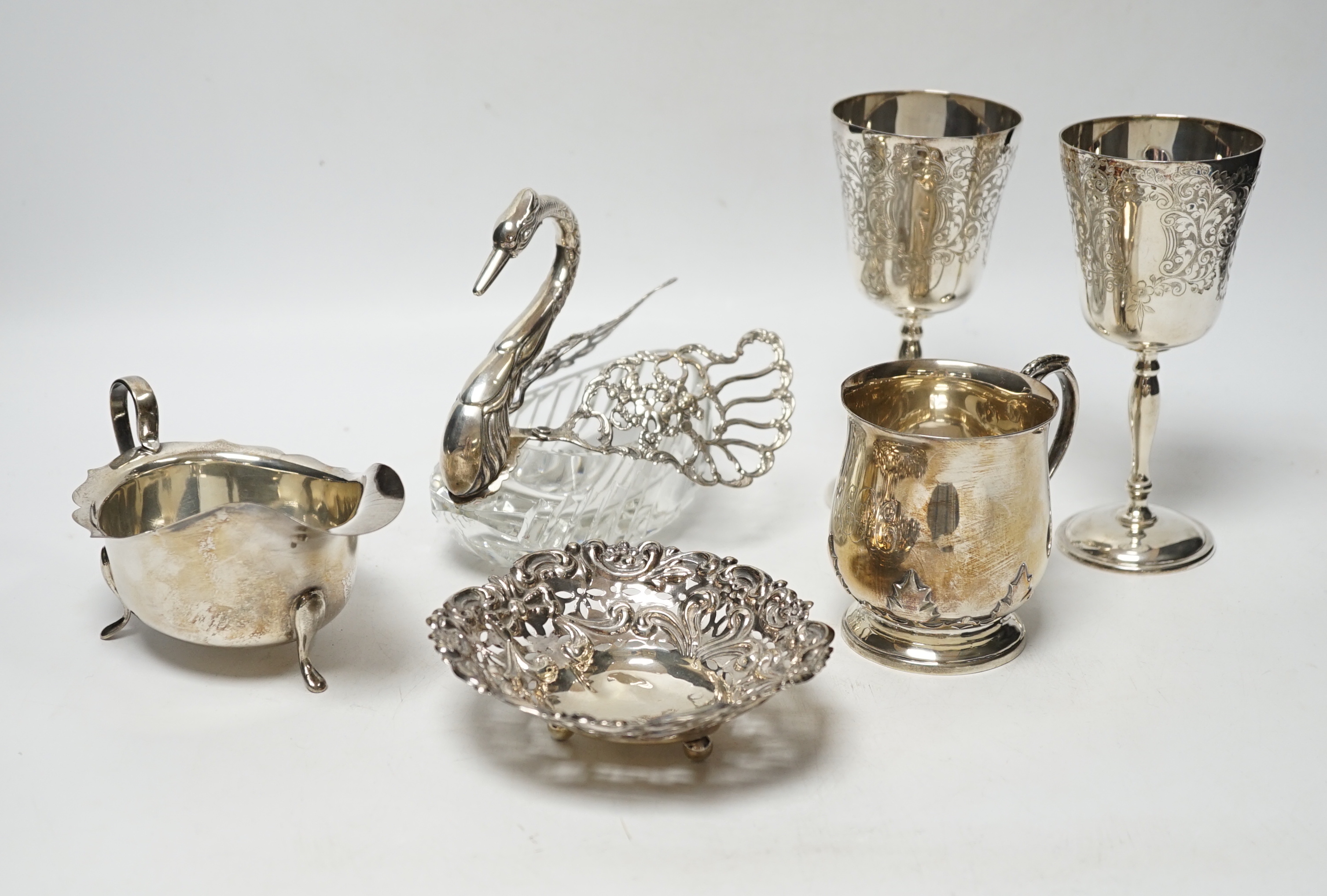 A George V silver christening mug, with card cut decoration, Adie Bros. Birmingham, 1903, height 81mm, a silver sauceboat, a dish, a pair of modern silver goblets and a 1970's silver mounted glass 'swan' bonbon dish.